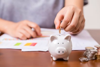 Female hand putting money into piggy bank for saving money.